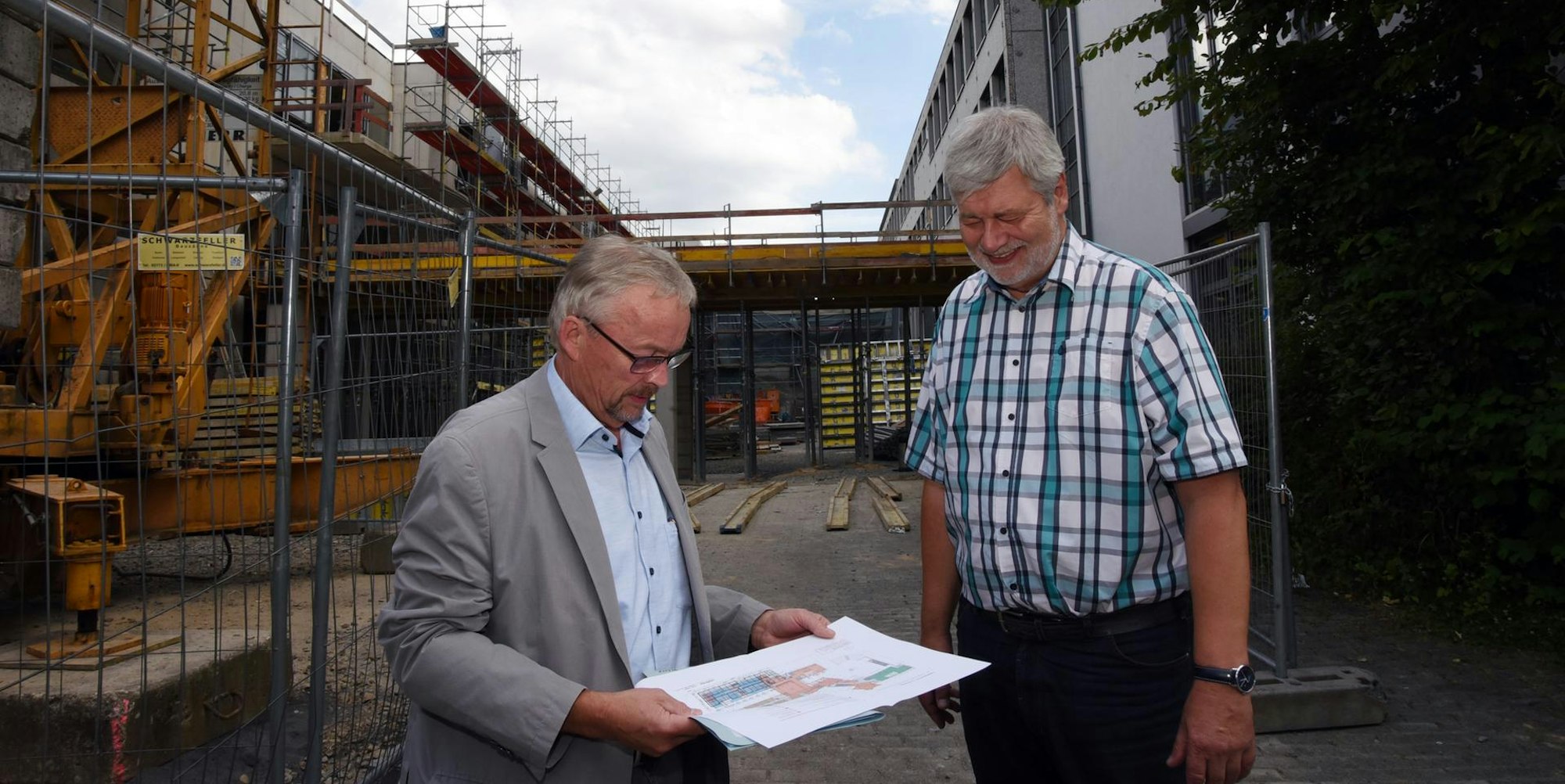 Bürgermeister Hilko Redenius (r.) und Bauamtschef Manfred Schneider stehen vor dem Neubautrakt (links) und der Sekundarschule (rechts).