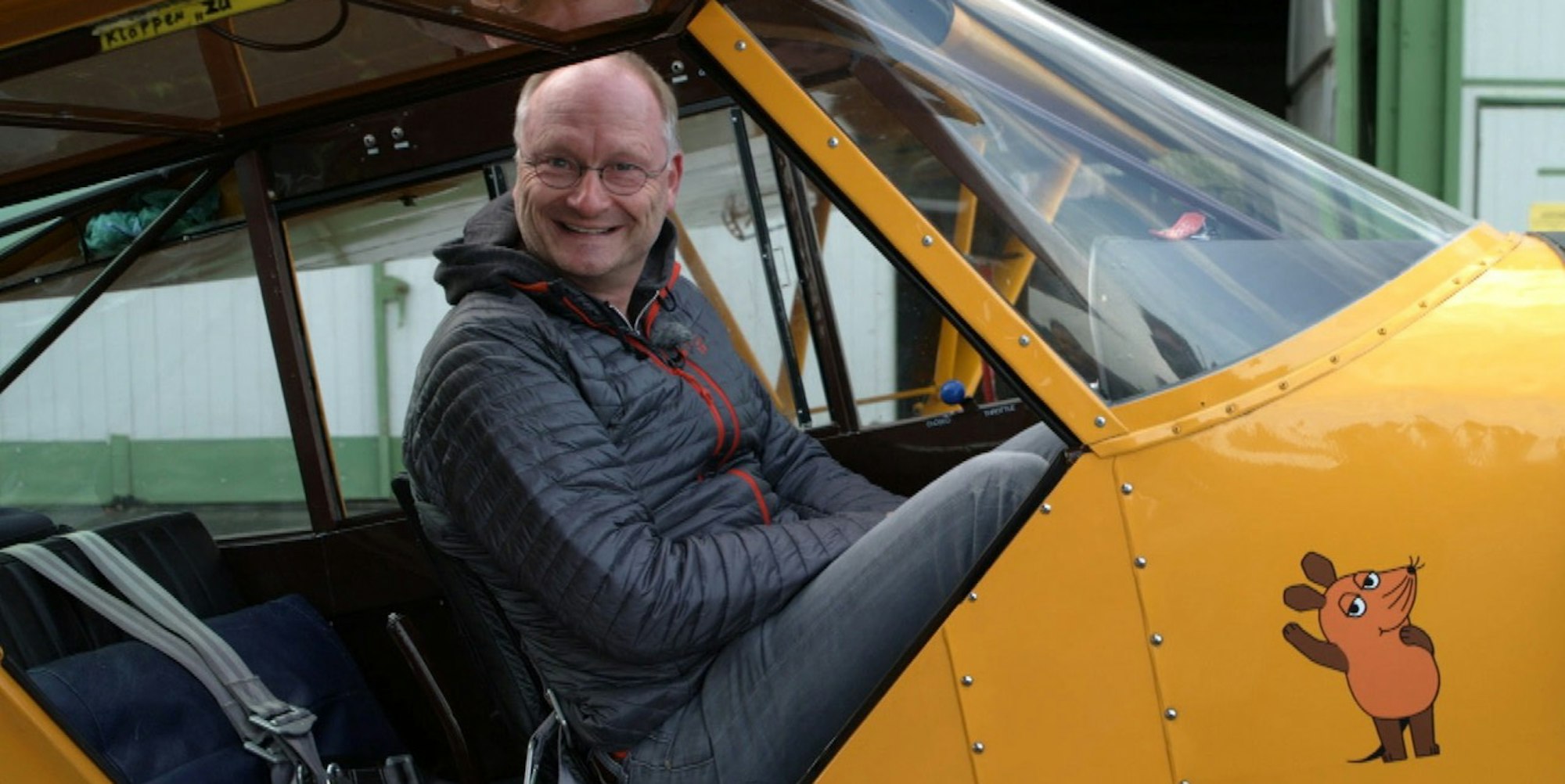 Sven Ploeger sitzt in einem gelben Flugzeug.
