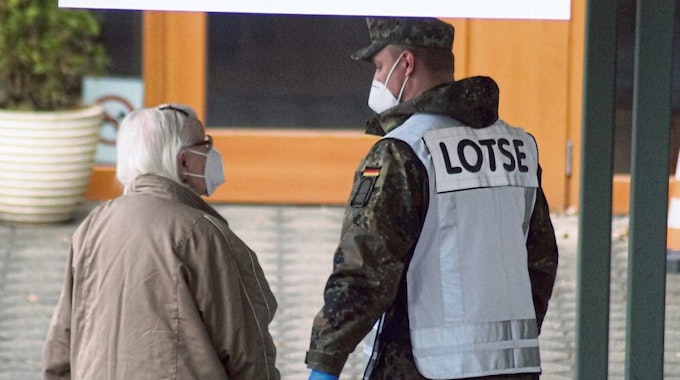 Freund und Helfer in Camouflage: Ein Soldat der Bundeswehr begleitet eine Seniorin zum Eingang.