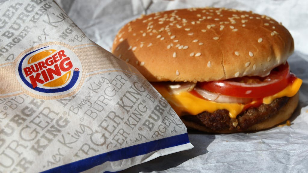 Ein Burger liegt neben einer Burger-King-Verpackung.