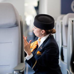 Eine Flugbegleiterin checkt die Sitzreihen eines Flugzeugs (Symbolbild)
