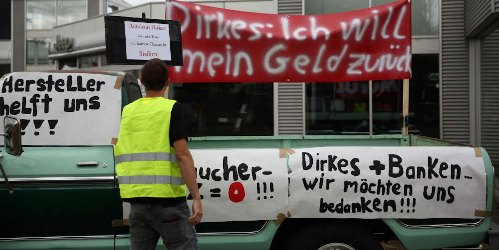 Auf Transparenten machten die Kunden des insolventen Autohändlers Dirkes vor der Filiale in Ehrenfeld ihrem Ärger Luft.