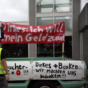 Auf Transparenten machten die Kunden des insolventen Autohändlers Dirkes vor der Filiale in Ehrenfeld ihrem Ärger Luft.