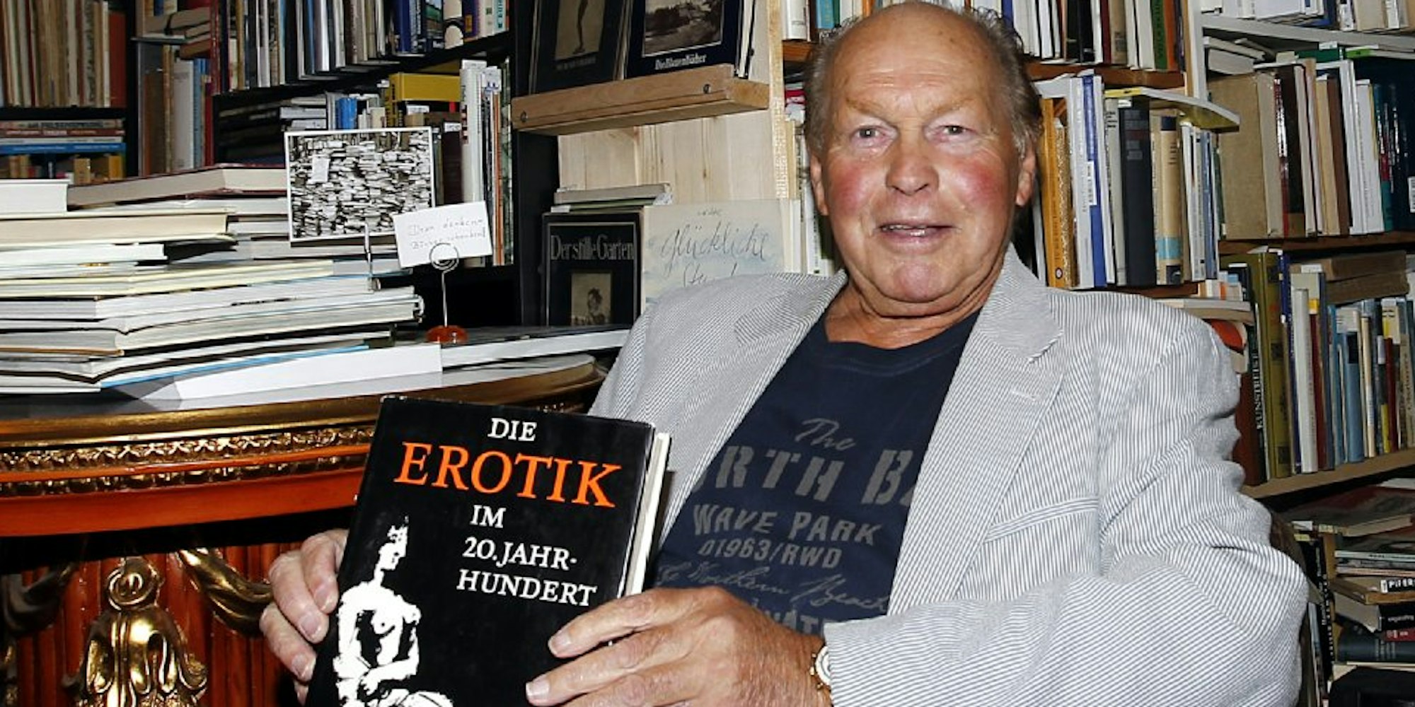 Er ist jetzt 77, ein Rentner. Hans Münnichhoff hält ein Erotikbuch in der Hand: Das Sex-Geschäft machte ihn einst reich.