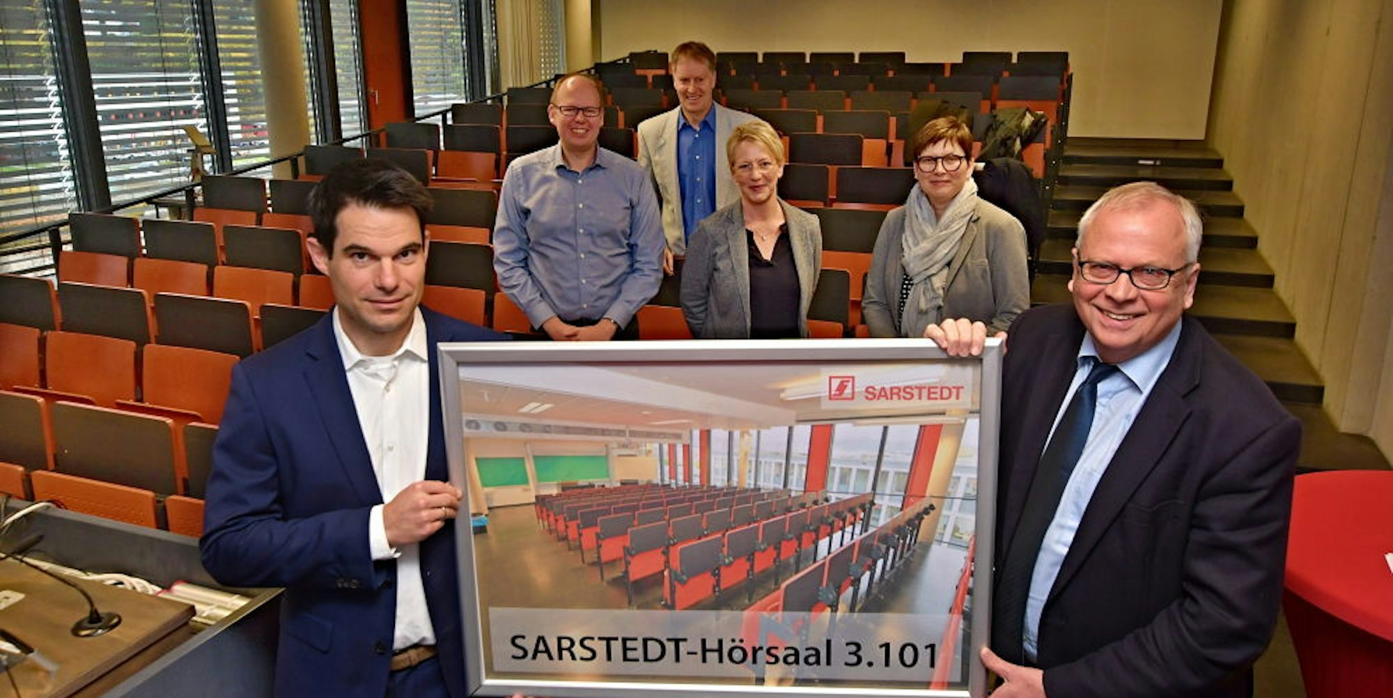 Das Schild zum Hörsaal zeigen Timo Schretzmair (l.) Vorstand Finanzen Sarstedt, und Dekan Prof. Dr. Christian Averkamp.