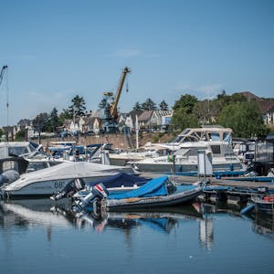 Boote im Yachthafen spiegeln sich auf der glatten Wasseroberfläche, die Sonne brennt – Hitdorf könnte auch am Mittelmeer liegen.