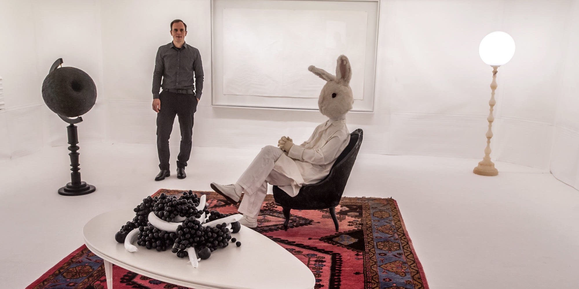 Wie bei „Alice im Wunderland“: Künstler Simon Schubert steht im weißen Hasenzimmer der Ausstellung „Schattenreich“.