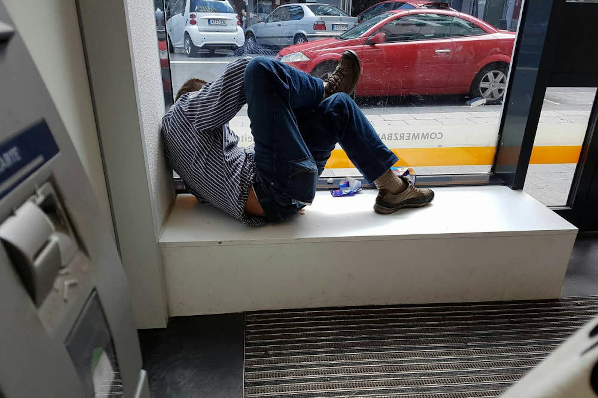  Der Rausch wird von einigen Obdachlosen im Au­to­ma­ten­raum einer Bank ausgeschlafen.
