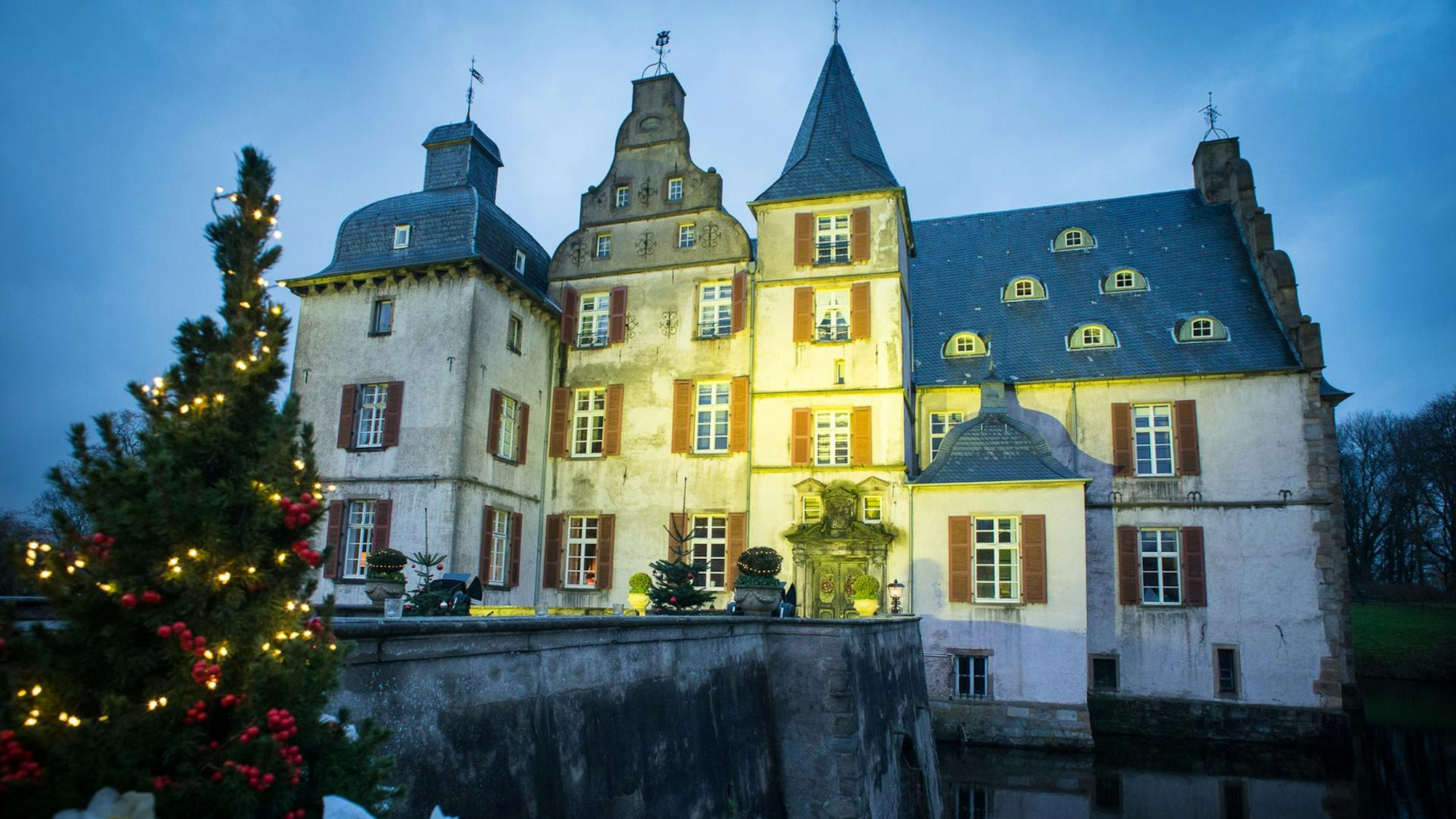 Beleuchtetes Wasserschloss mit Tannenbaum im Vordergrund, Schloss Bodelschwingh