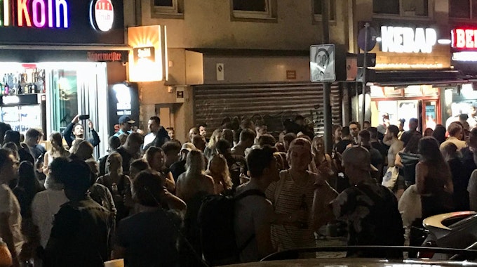 Viele Leute stehen dicht gedrängt vor einem Kiosk und anderen Lokalen an der Zülpicher Straße, Ecke Zülpicher Platz