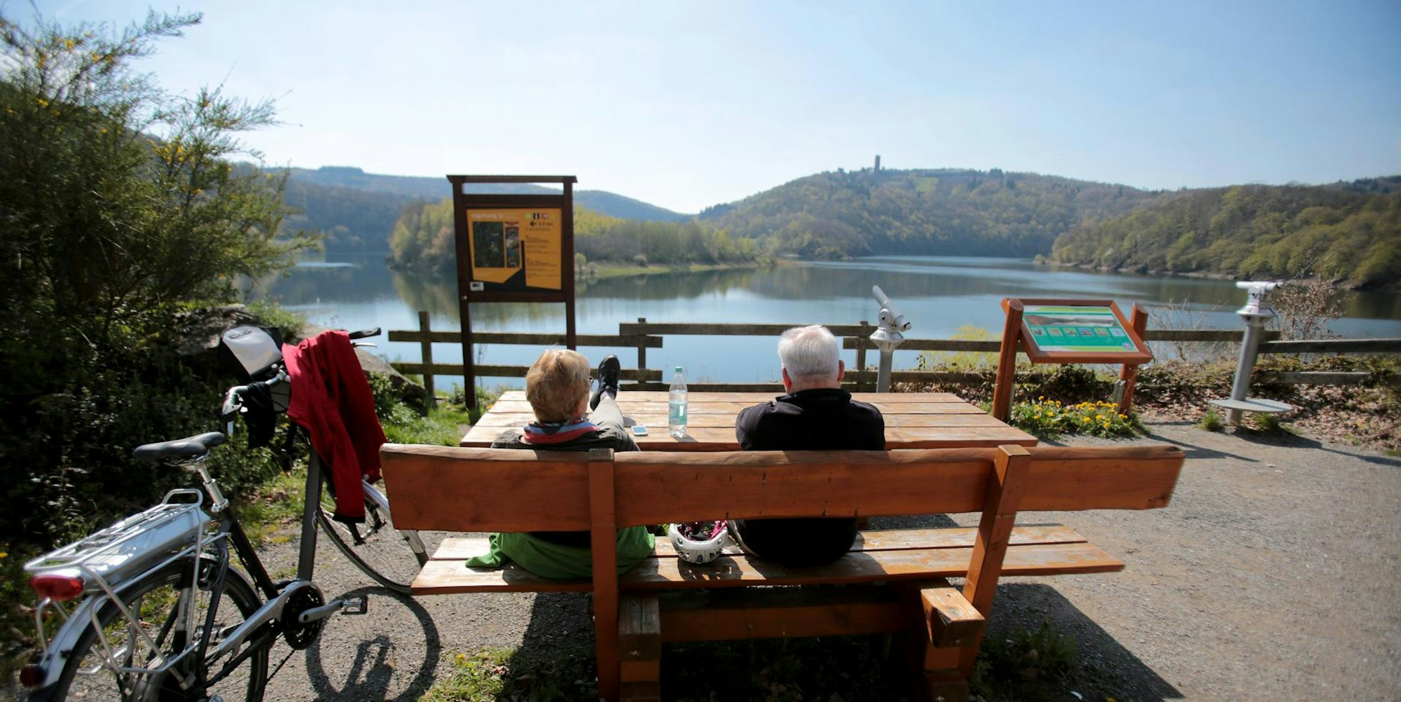 NRW bietet viele Möglichkeiten zum Wandern oder Mountainbiken – hier picknicken zwei Radfahrer am Urftsee im Nationalpark Eifel.