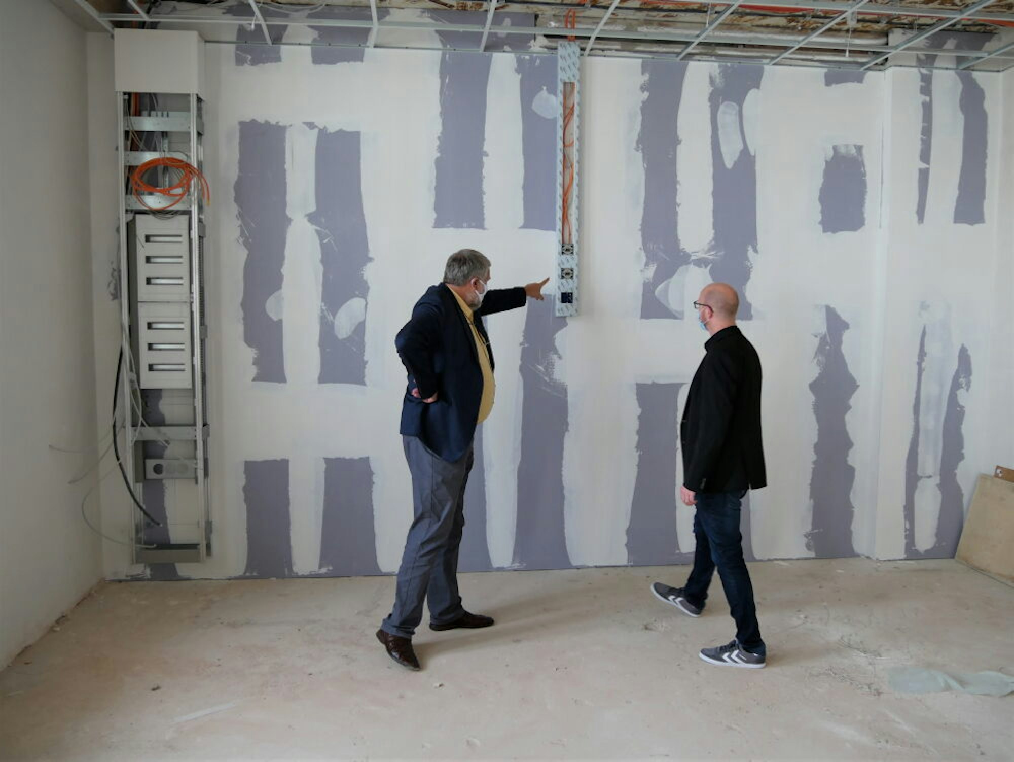Schulleiter Gerog Jöbkes (l.) zeigt Bürgermeister Ingo Pfennings, wo einer der Großbildschirme angeschlossen werden.