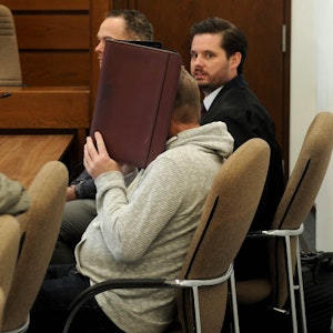 Der Täter im Gerichtssaal hinter einer Mappe