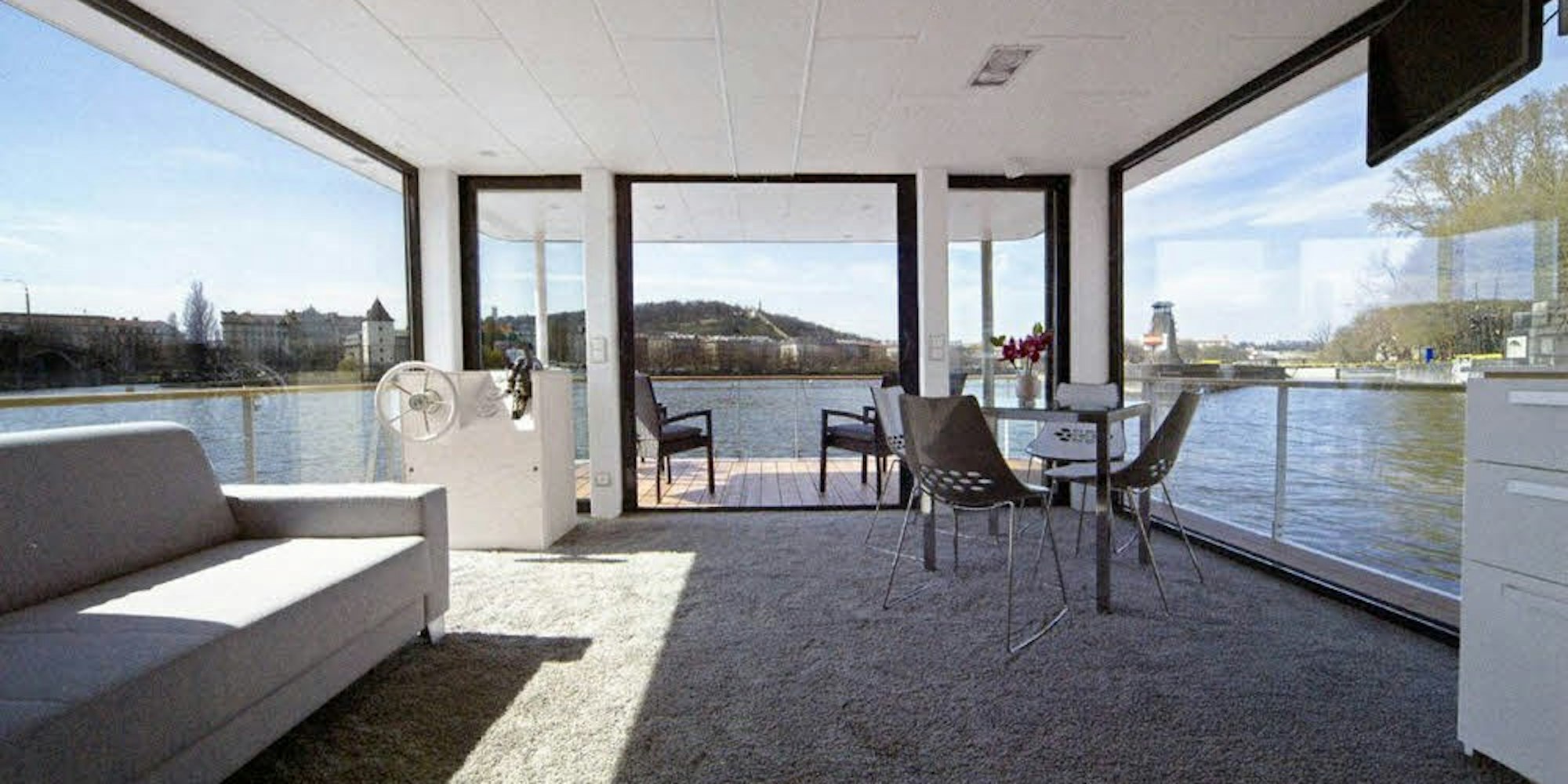 Komfort und Ausblick: Raumhohe Fenster und ein offener Wohnbereich mit Küchenzeile sorgen für modernes Wohlfühl-Ambiente.
