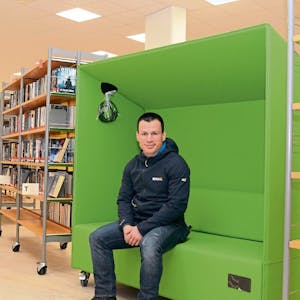 Die grünen Möbel sind wie das gesamte Mobiliar zum Rollen. Bibliotheksleiter Philipp Maaß sitzt schon einmal Probe.