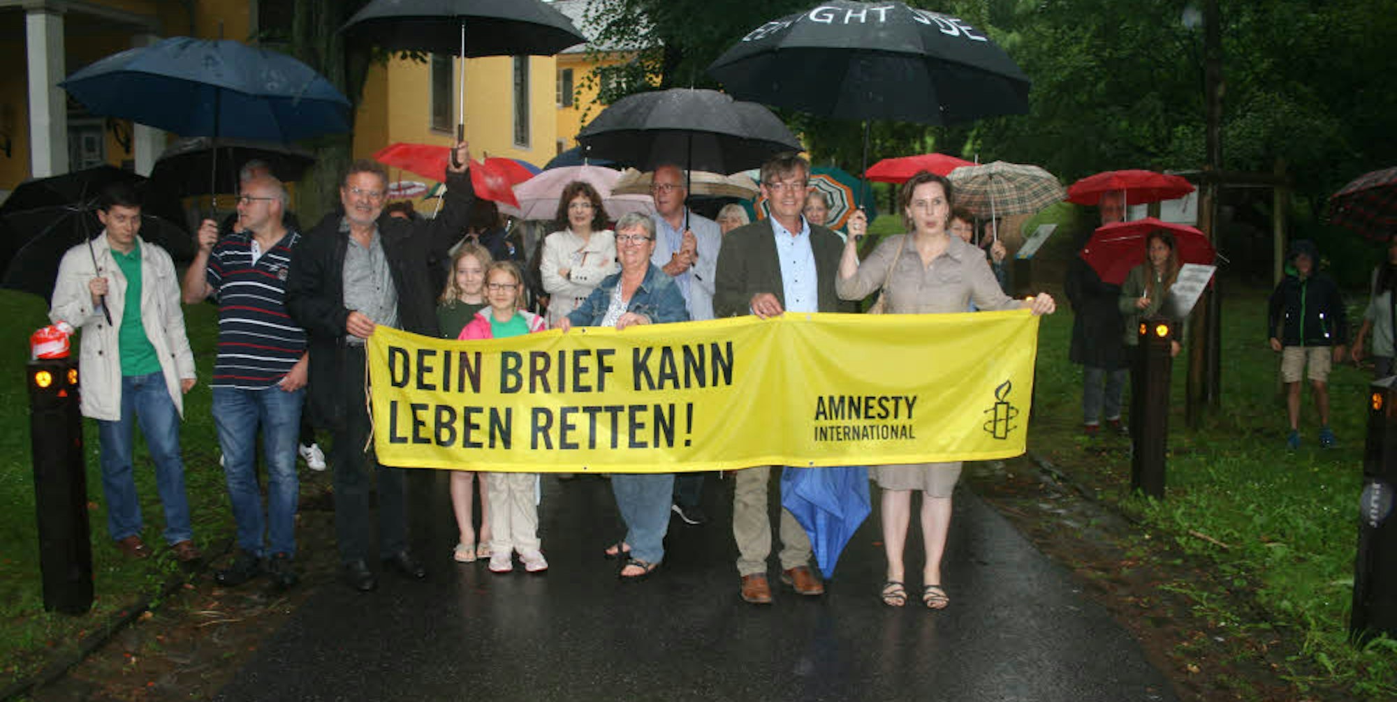 Aktion im Regen: Die Gladbacher Gruppe von Amnesty International weiht das Mahnmal ein.