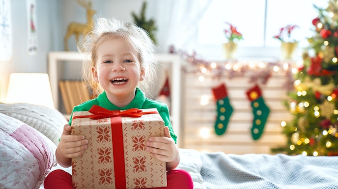 Ein Mädchen hält lachend ein Geschenk in den Händen.