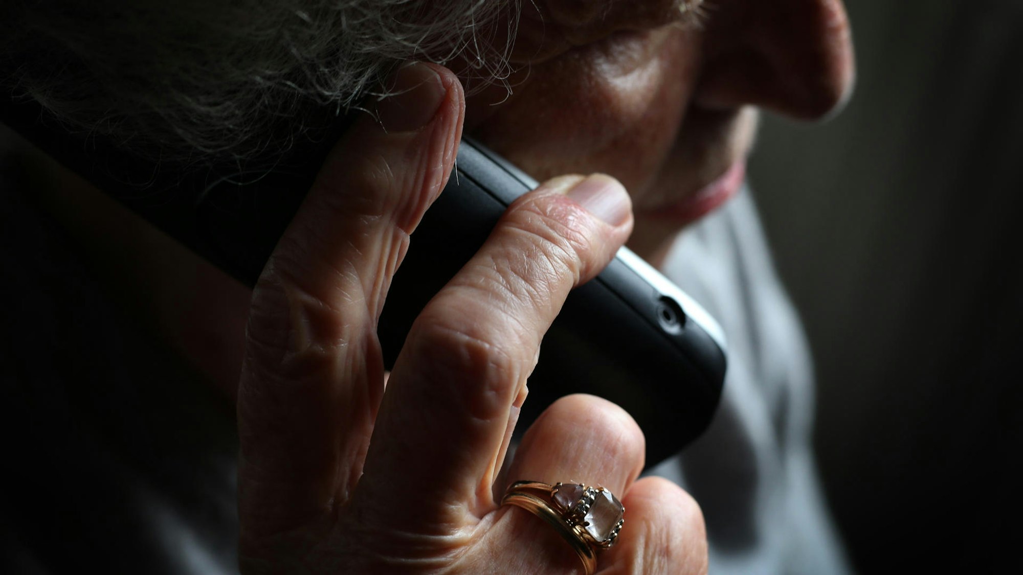 Das Symbolbild zeigt eine ältere Frau mit einem Telefonhörer in der Hand.