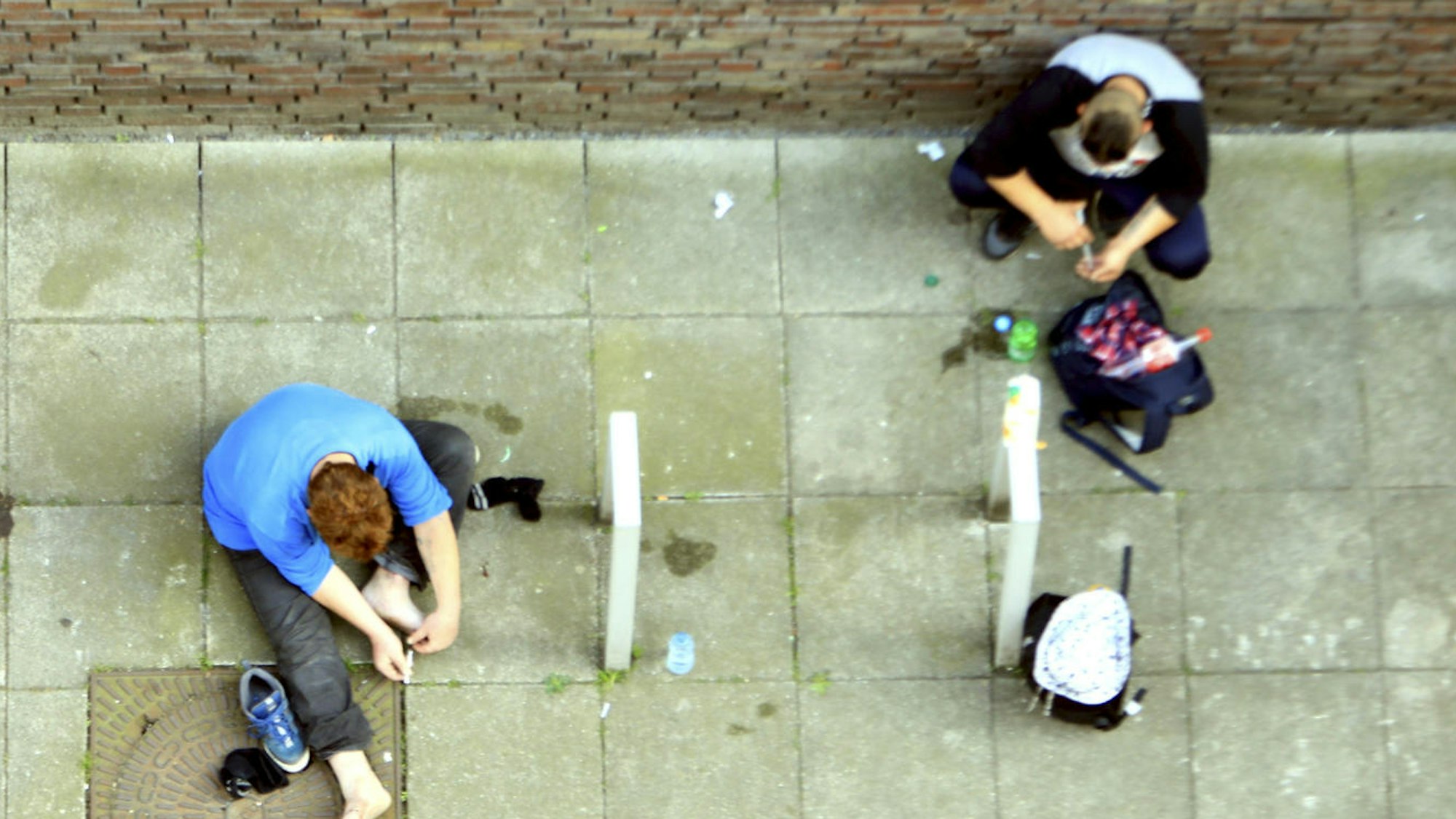 Zwei Männer sitzen auf dem Boden und konsumieren Heroin.