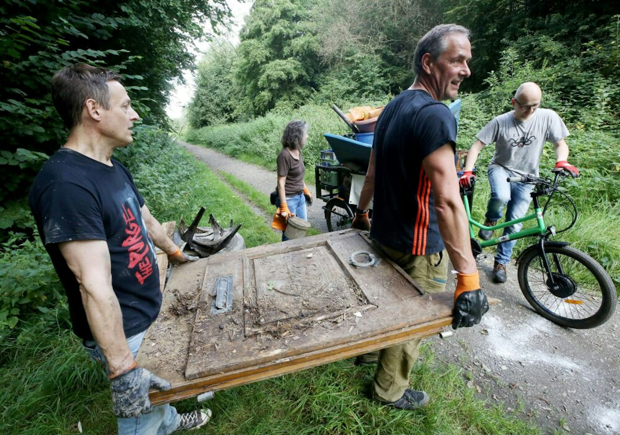 Freiwillige Helfer tragen eine am Rheinufer gefundene Tür mit Weinmotiv zur Sammelstelle.