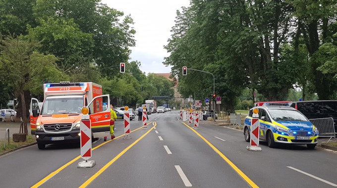 Ein Rettungswagen und ein Streifenwagen stehen auf einer Straße. In Köln-Zollstock soll eine Radfahrerin am Mittwoch ein Kind auf einem Fahrradweg angefahren und anschließend Unfallflucht begangen haben.