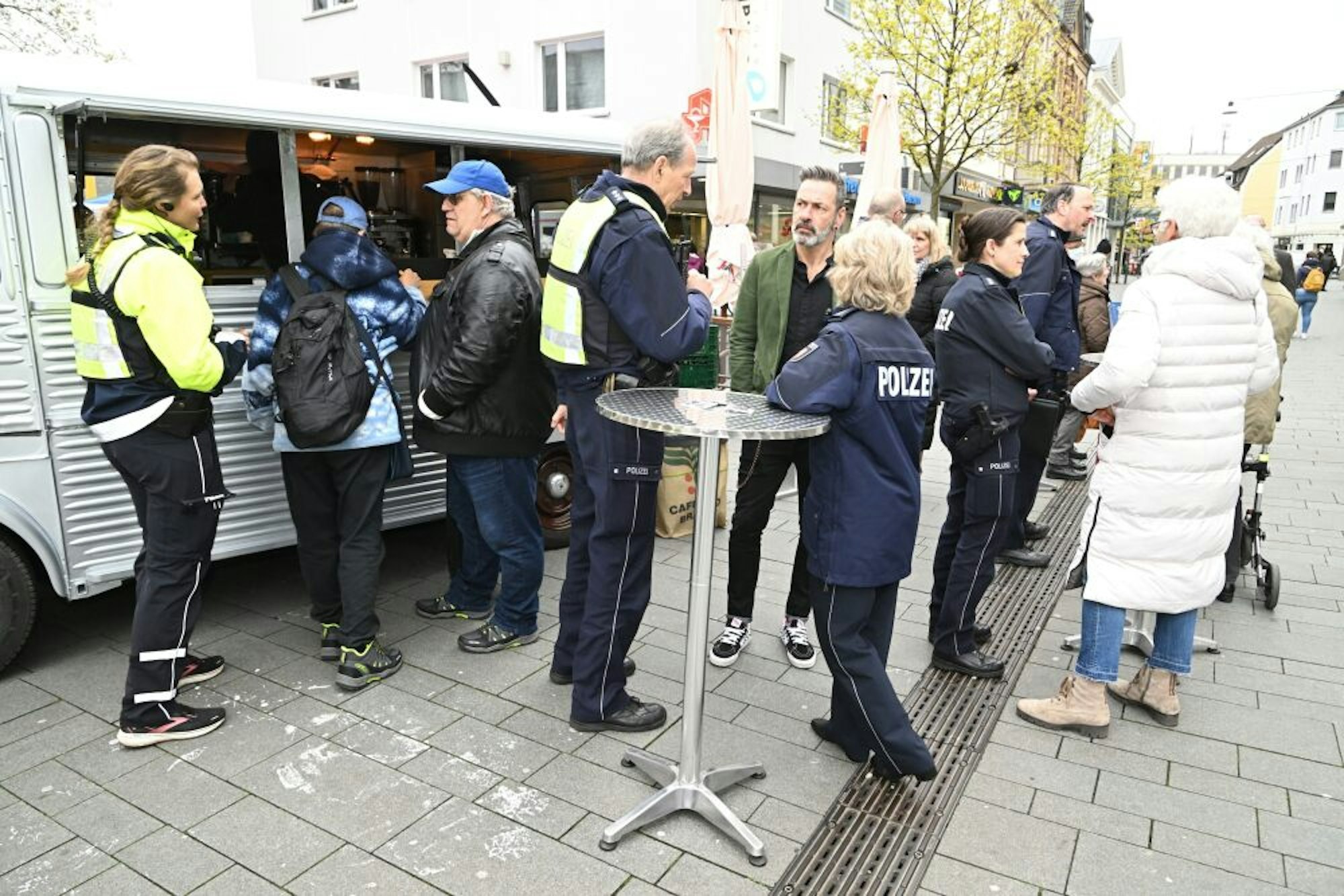 NRW-Innenminister Herbert Reul (linkes Bild, l.) im Gespräch mit Helga Henk (r.) und Claudia Kammann. Am Café-Mobil (rechtes Bild) kamen am Mittwoch zahlreiche Bürgerinnen und Bürger mit der Polizei „auf einen Kaffee“ ins Gespräch.