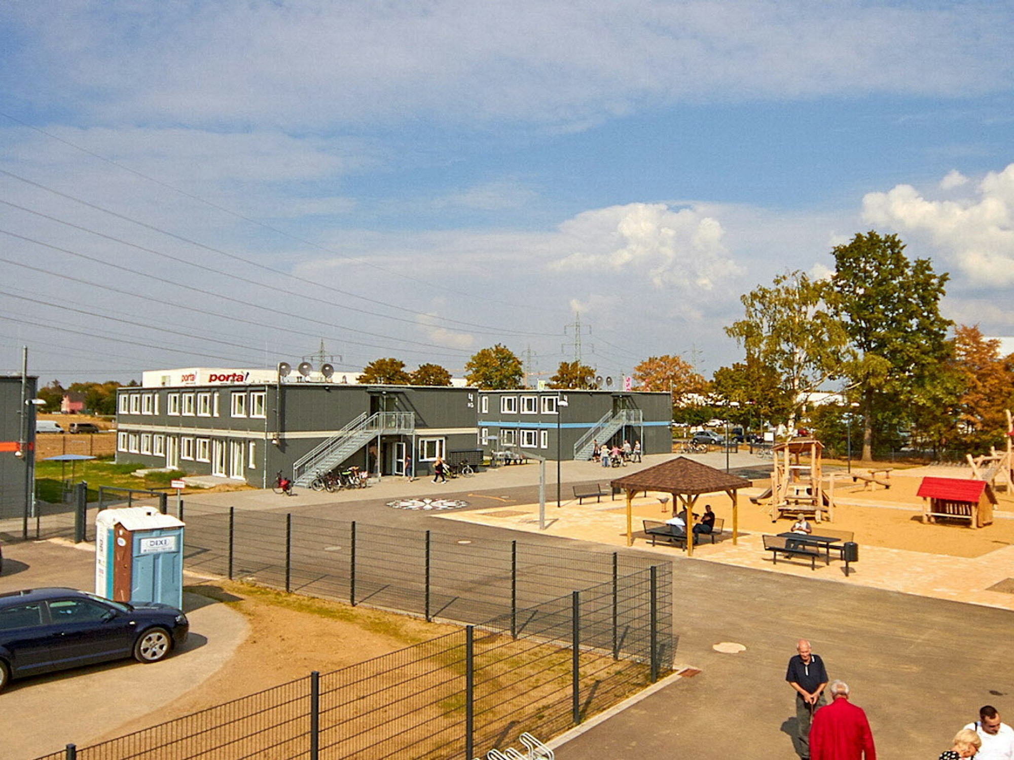 Die neue Unterkunft für Geflüchtete (links) gegenüber dem Möbelhaus Porta (Mitte) besteht aus fünf doppelstöckigen Containerbauten und einem Spielplatz. (rechts).