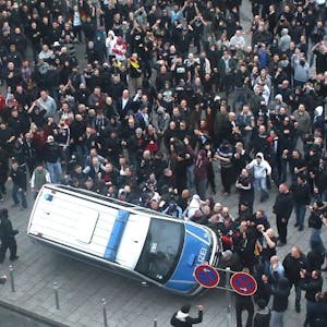 Demonstranten werfen während der Ausschreitungen in Köln ein Polizeiauto um.