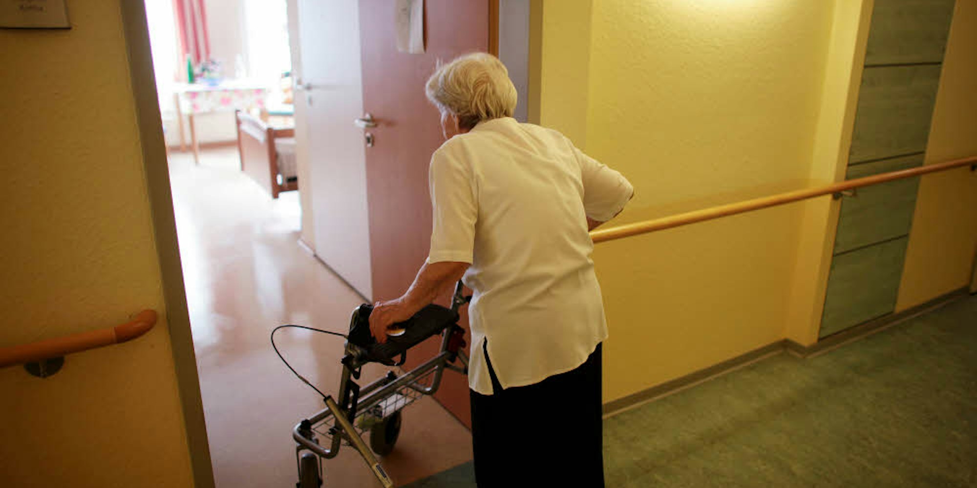 Eine Frau betritt mit ihrem Rollator ihr Zimmer in einem Kölner Caritas-Seniorenheim.