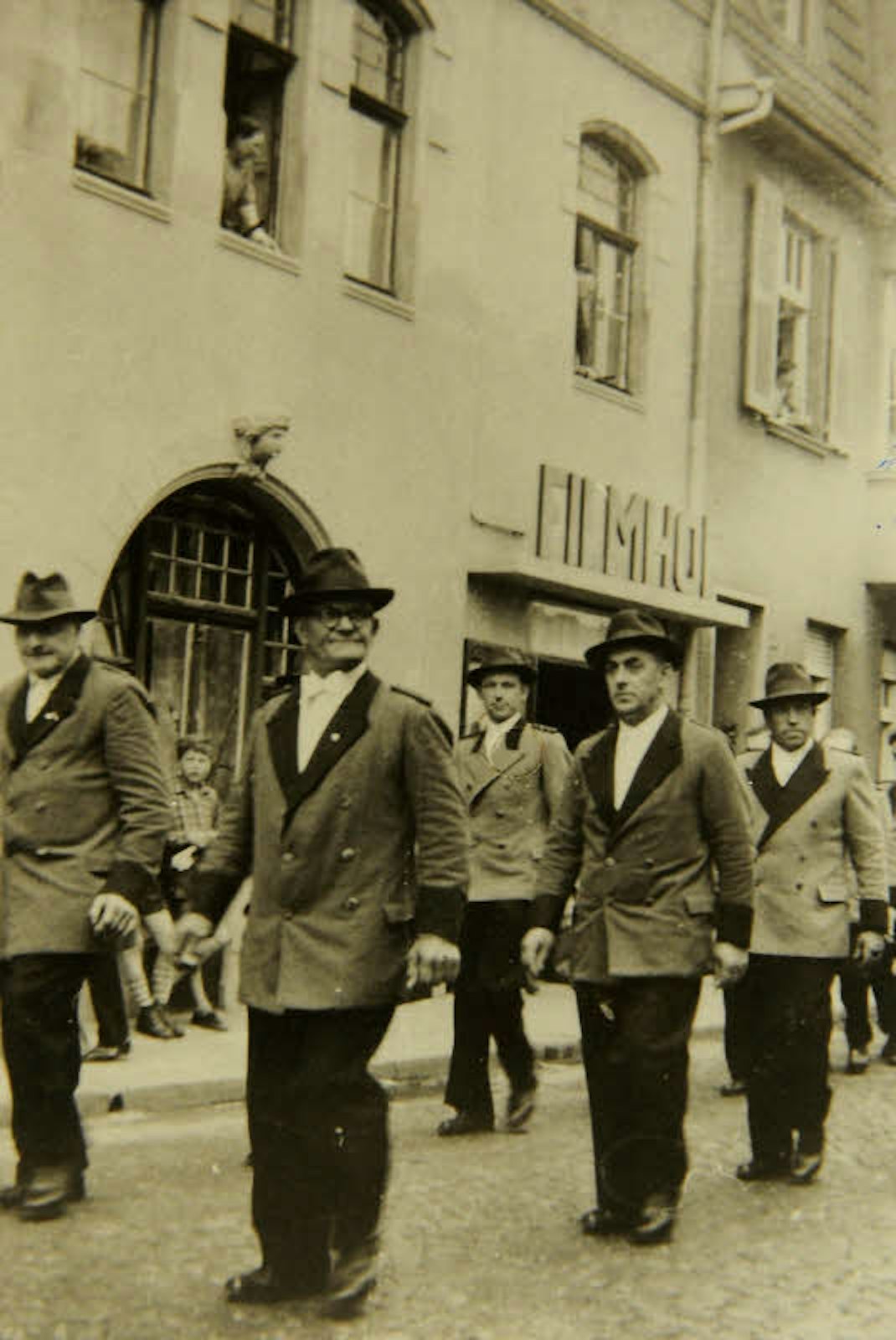 Schützen passieren in den 50er Jahren das Kino „Filmhof-Lichtspiele“ an der Gisbertstraße 83-85 in Stammheim.