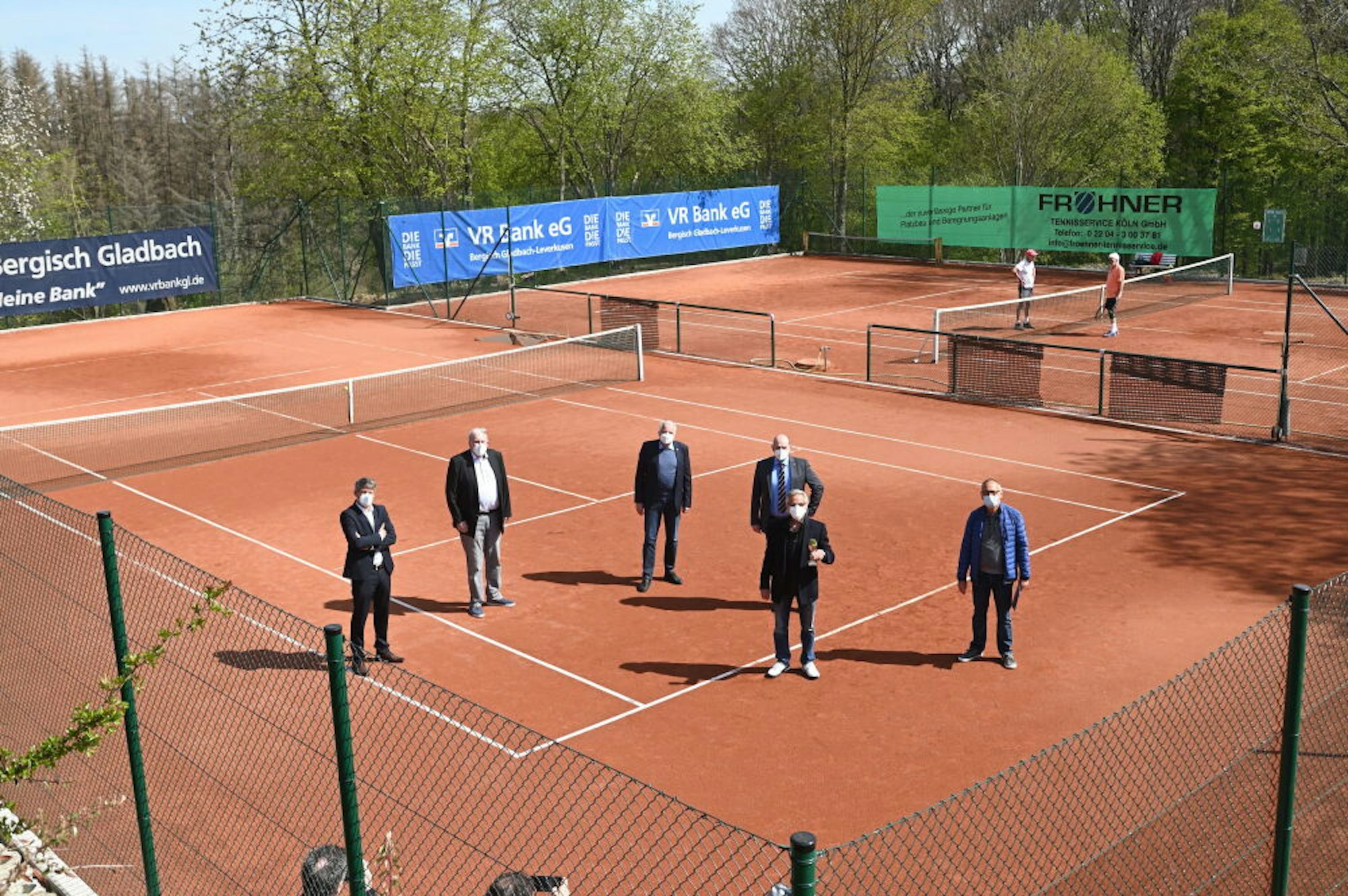 Die glücklichen Funktionsträger stehen auf dem sanierten Tennisplatz.