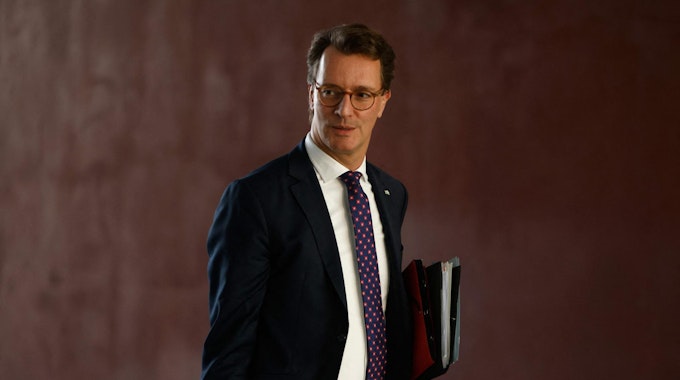 NRW-Ministerpräsident Hendrik Wüst trägt eine Aktenmappe.