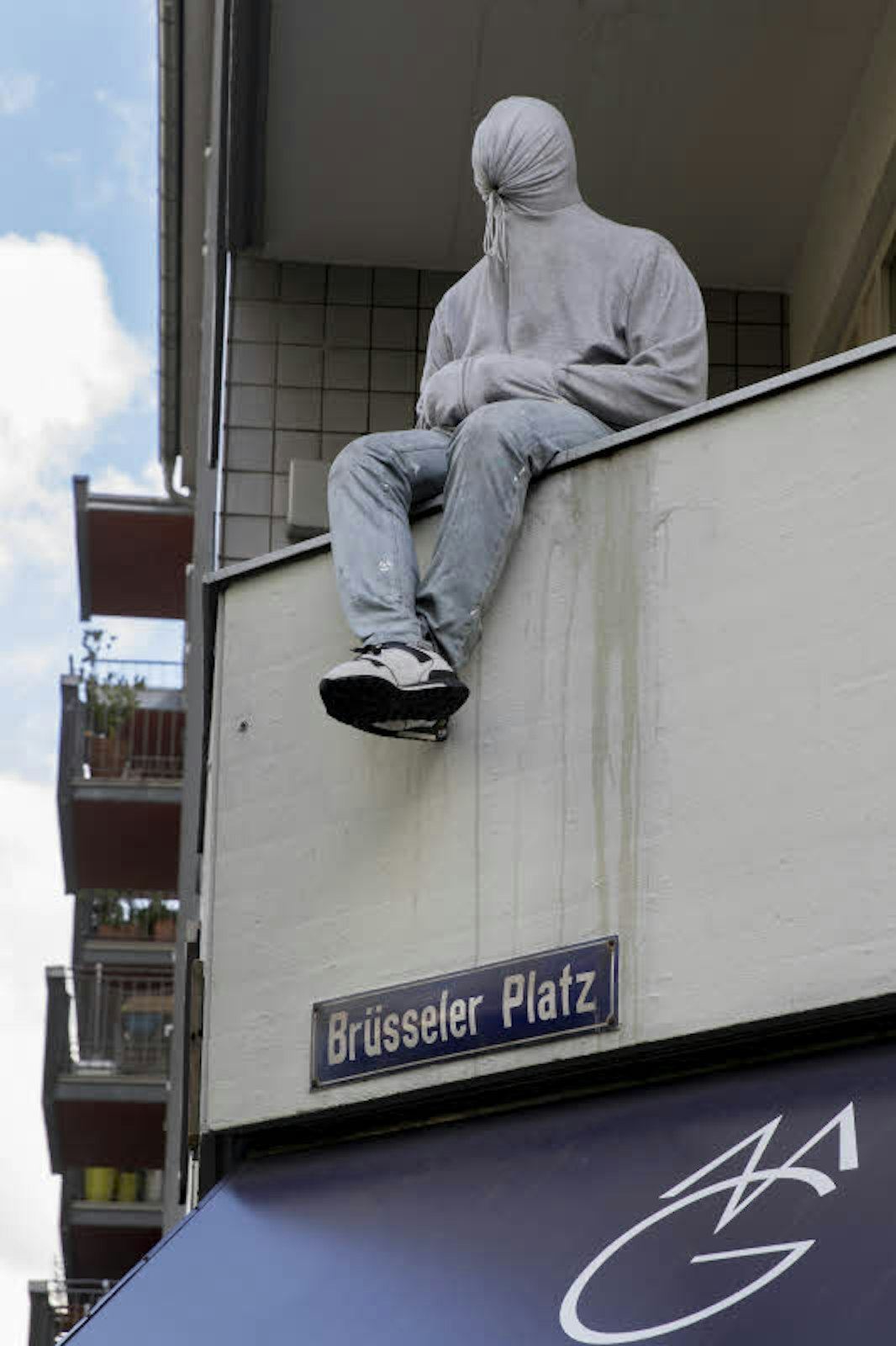 Lebensechte Balkon-Skulptur – ein Blickfang am Brüsseler Platz.