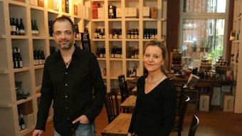 Die Besitzer des Weinrestaurants Pradels in ihrem Laden vor Weinen im Weinregal