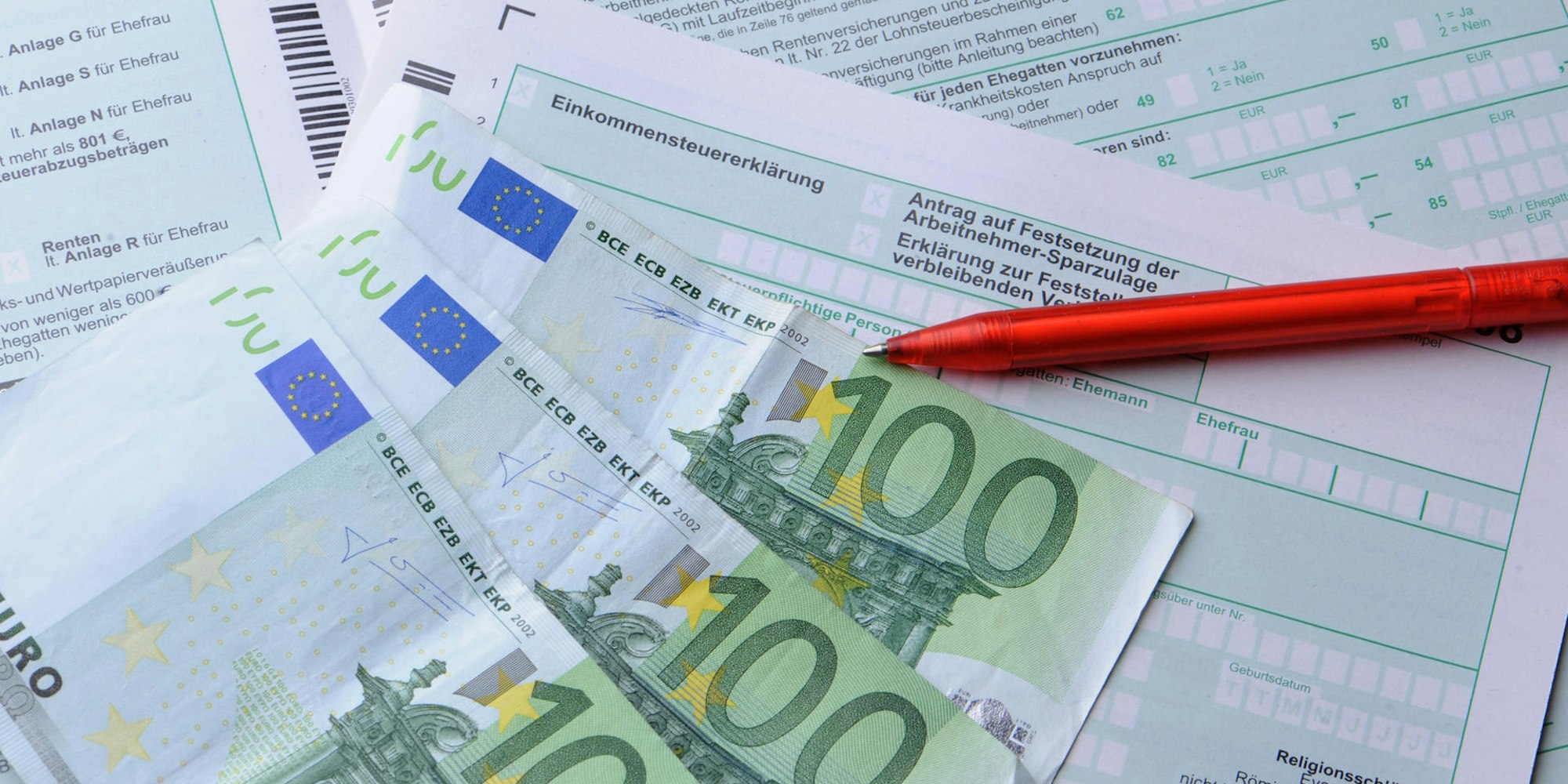 Geldscheine und ein Stift liegen auf einem Formular für die Steuererklärung.