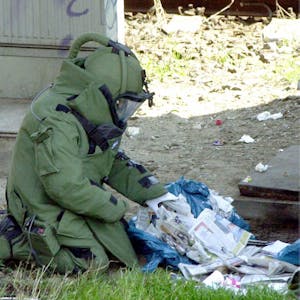 Ein Sprengstoffexperte in Splitterschutzkleidung überprüft verdächtige Mülltüten in der Nähe des Attentatsortes.