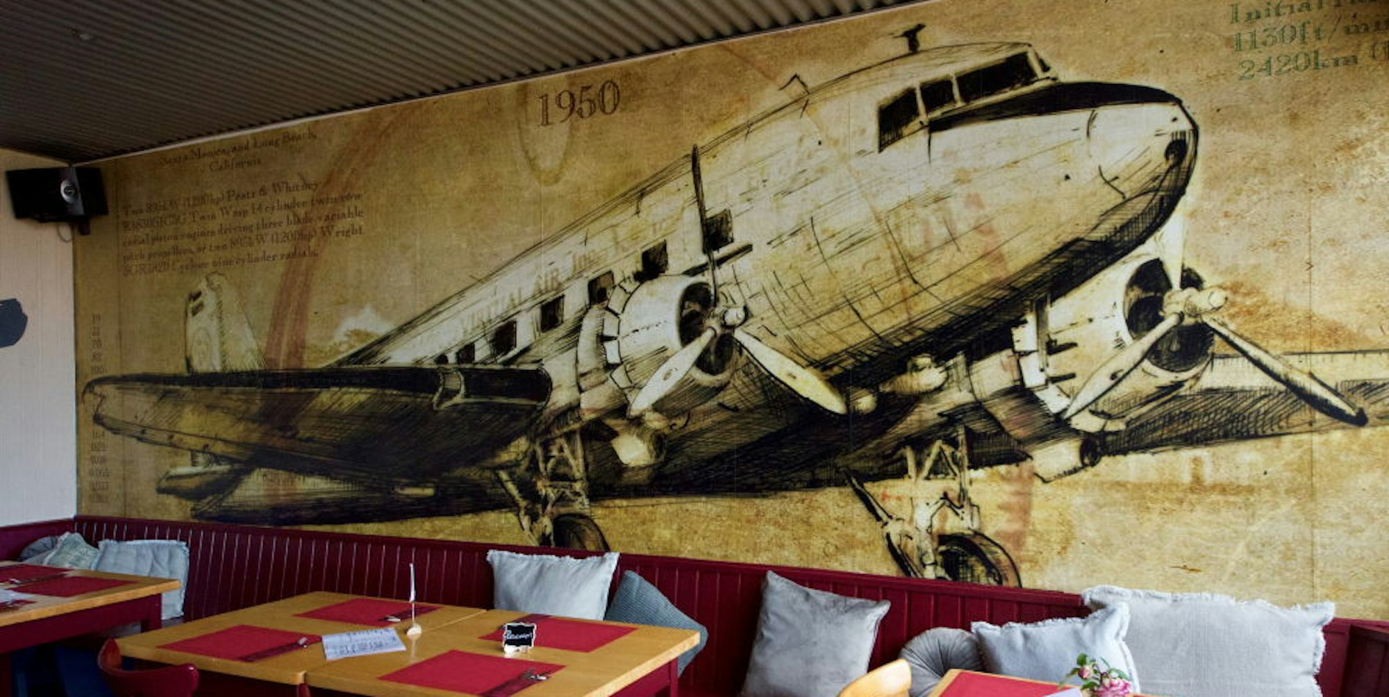 Eine Douglas DC-3 an der Rückwand des Hangars, wie der große Restaurantraum genannt wird, verweist auf das Fliegerei-Umfeld.