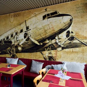 Eine Douglas DC-3 an der Rückwand des Hangars, wie der große Restaurantraum genannt wird, verweist auf das Fliegerei-Umfeld.