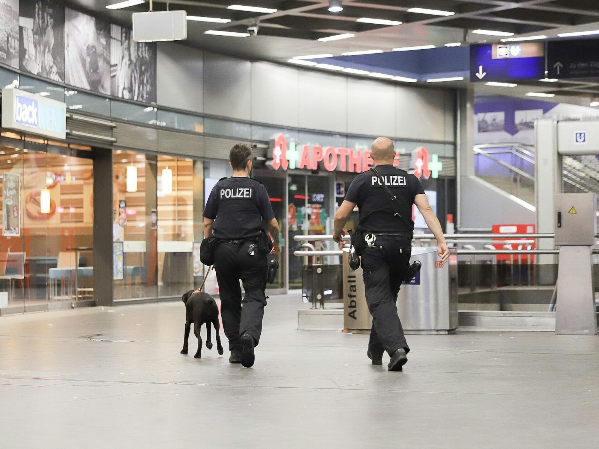 Polizisten laufen mit einem Diensthund durch den Hauptbahnhof Gelsenkirchen.