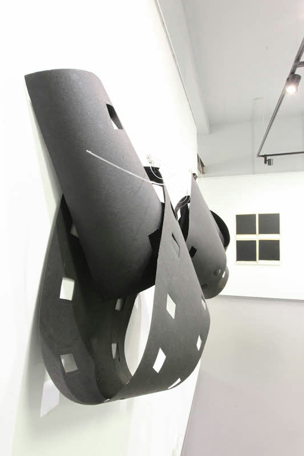 Ilse Wegmann beim Hängen ihrer Arbeiten im Troisdorfer Kunsthaus. Rechts ein Objekt mit Schattenwurf: überdimensionale Filmstreifen aus Pappe