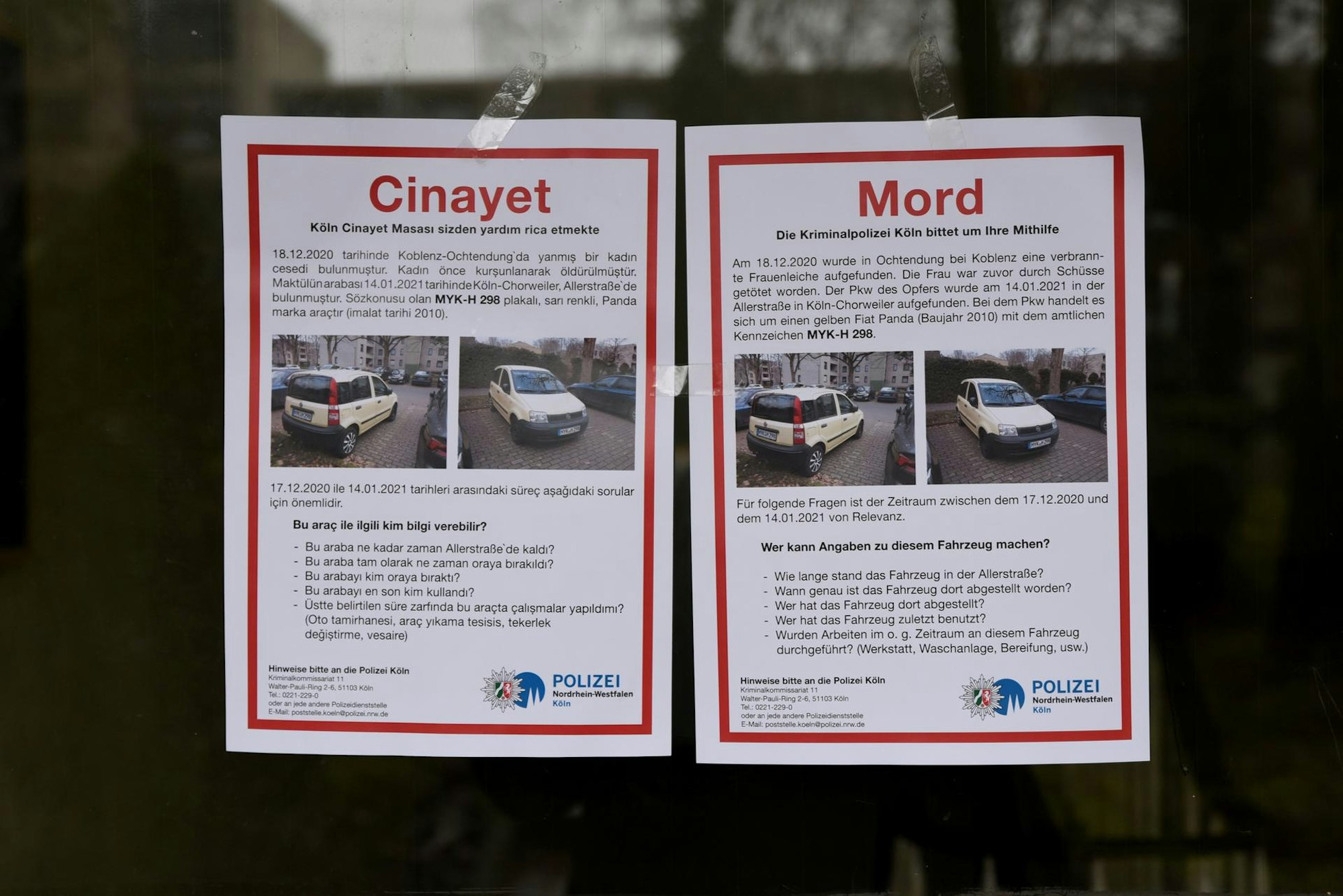 Zwei Zettel der Polizei mit Autofotos und der Bitte um Hinweise kleben an einer Glasscheibe.