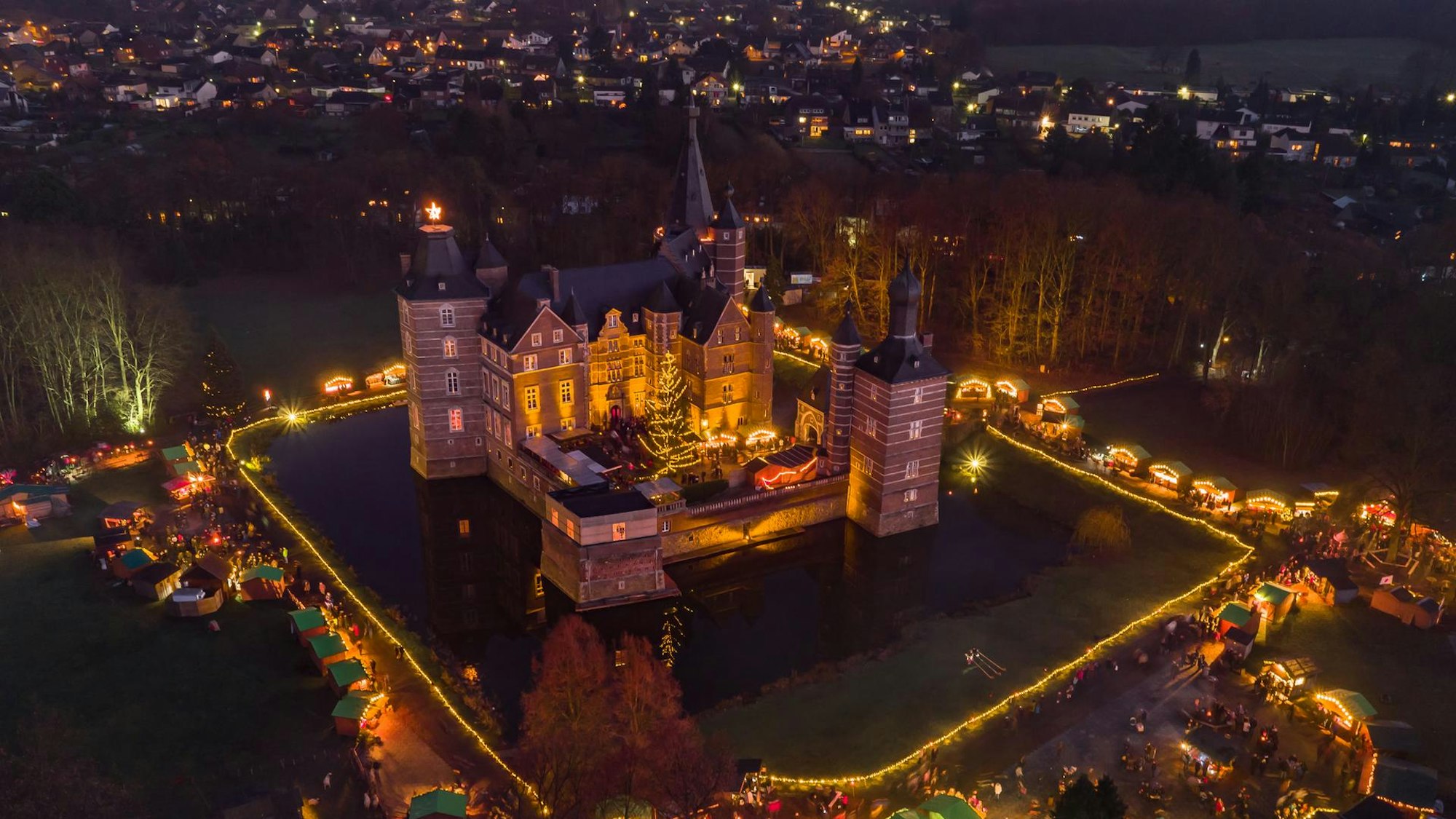 Luftaufnahme von Schloss Merode mit vielen Lichtern in der Nacht