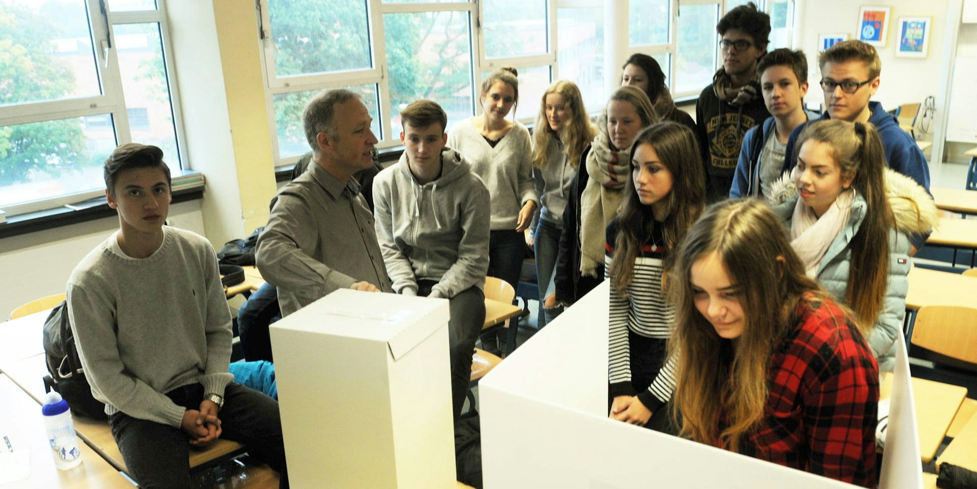 Lehrer André Linnenbaum (2.v.l.) bespricht mit seinen Schülern den Wahlakt.