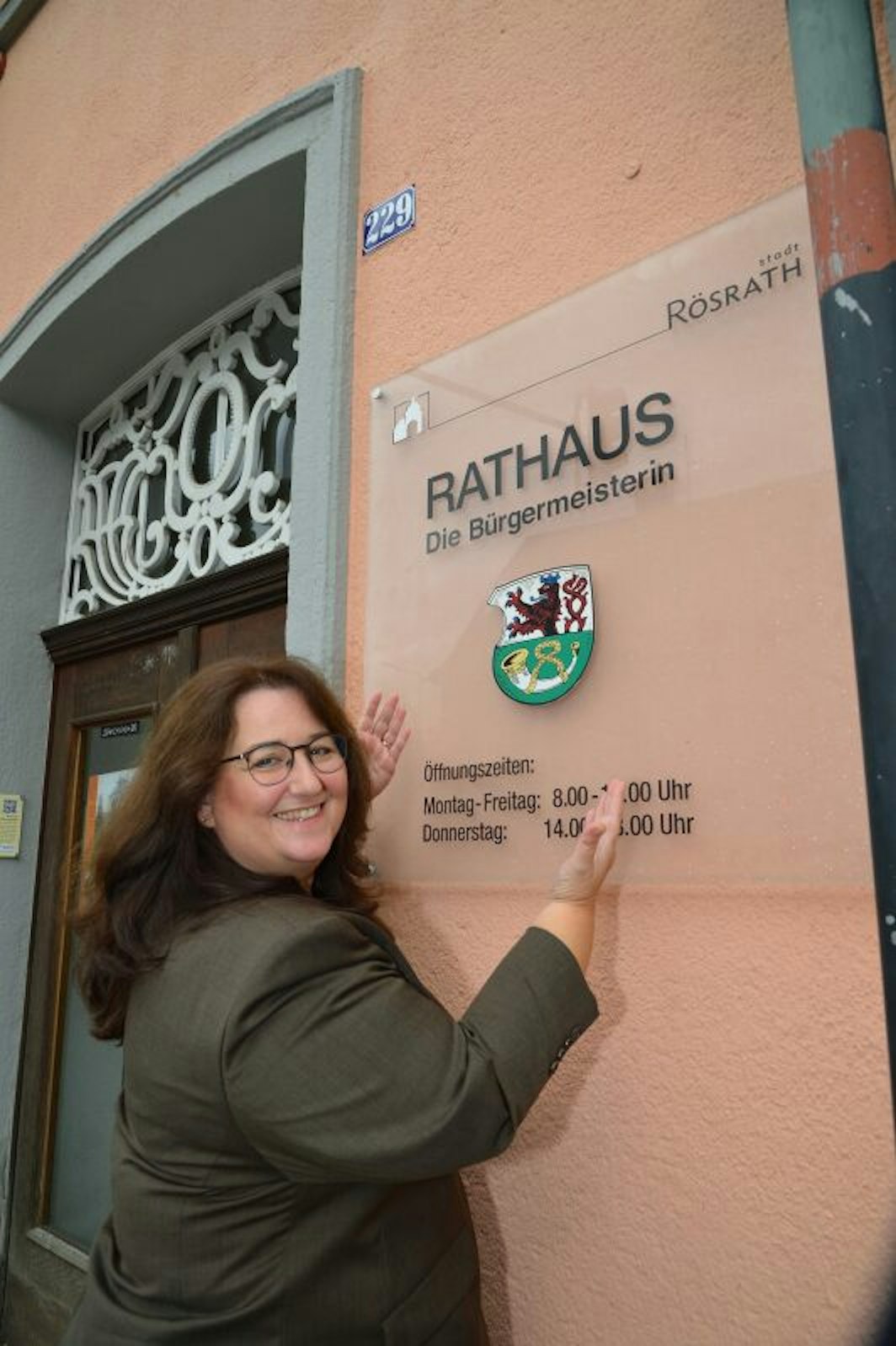 Dass erstmals eine Frau Stadtchefin ist, zeigt Bondina Schulze mit einem neuen Schild am Rösrather Rathaus.
