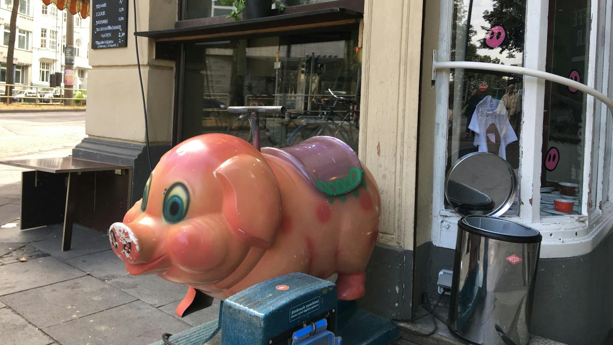 Ein kleines Schweine-Fahrgeschäft für Kinder vor der Caffé Bar