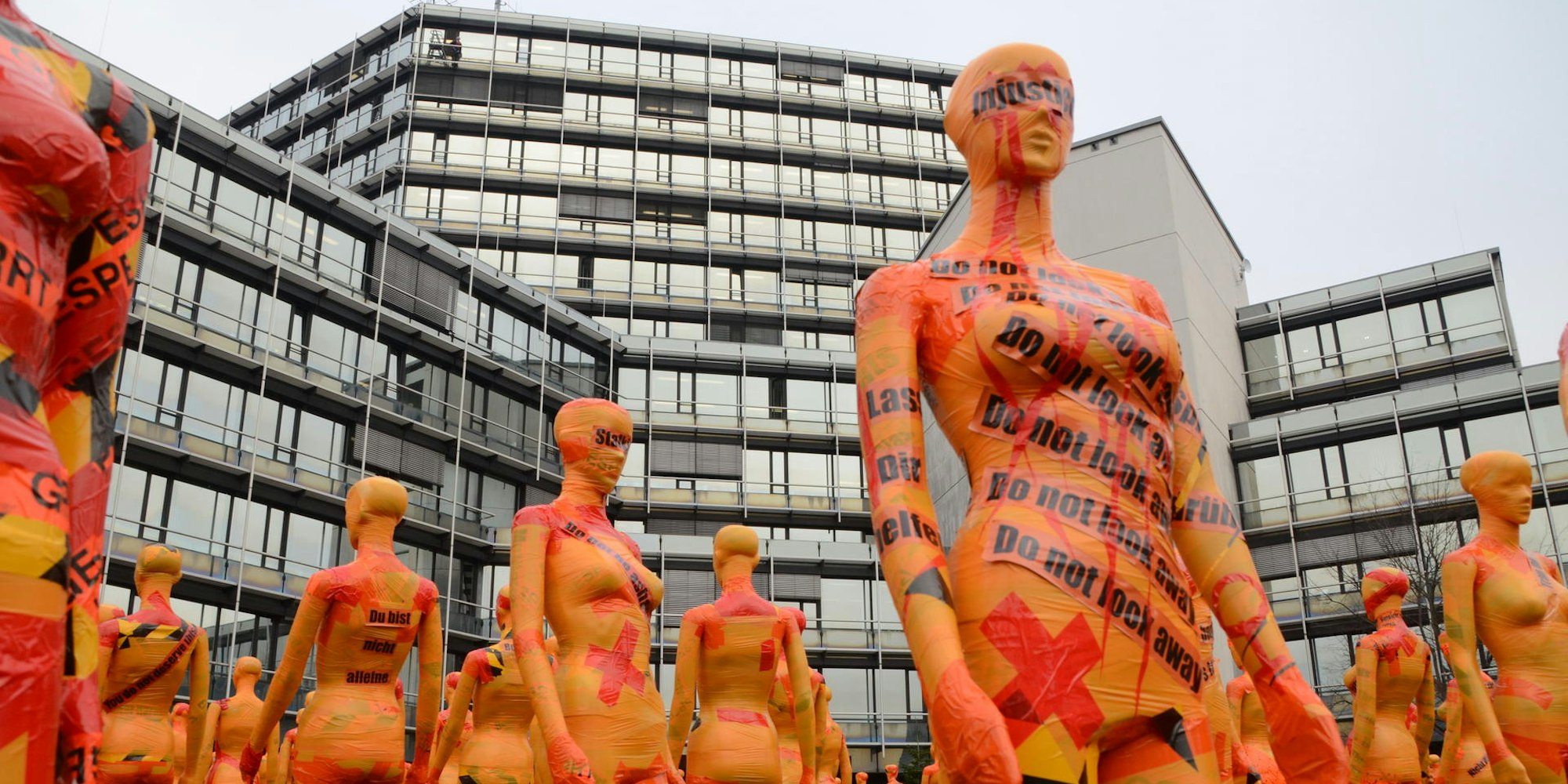222 Schaufensterpuppen in Orange und Rot stehen als Mahnwache gegen Gewalt an Frauen vor dem Siegburger Kreishaus.