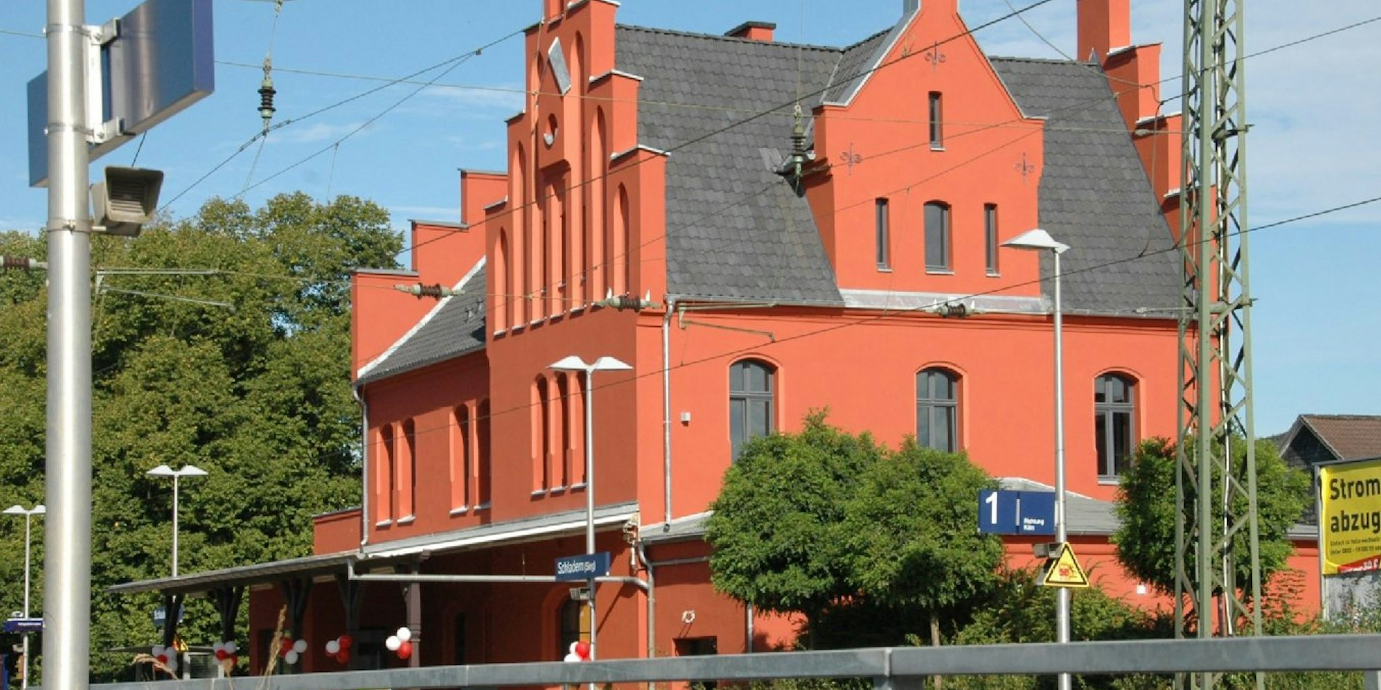 Der alte Schladerner Bahnhof leuchtet frisch renoviert rot in der Sonne.