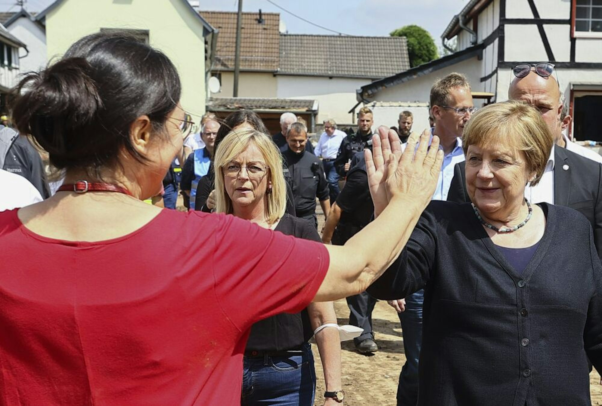 Eine Anwohnerin begrüßt Angela Merkel, die mit Bürgermeisterin Sabine Preiser-Marian (M). durch Iversheim geht.