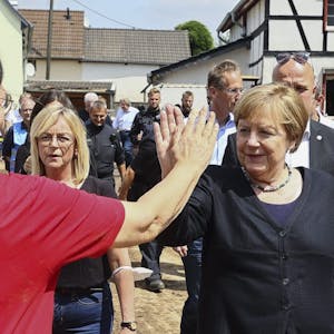 Eine Anwohnerin begrüßt Angela Merkel, die mit Bürgermeisterin Sabine Preiser-Marian (M). durch Iversheim geht.