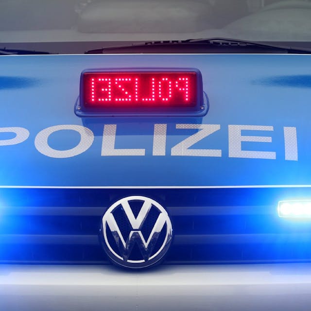 Ein Polizeiauto mit angeschalteten Scheinwerfern und Polizei-Schriftzug ist von vorne zu sehen.
